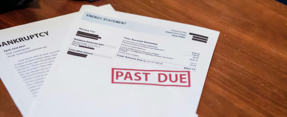 Close-up of a wooden table with a crumpled energy bill stamped 