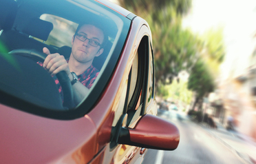 Driver in a red car looking at the road while refinancing his auto loan