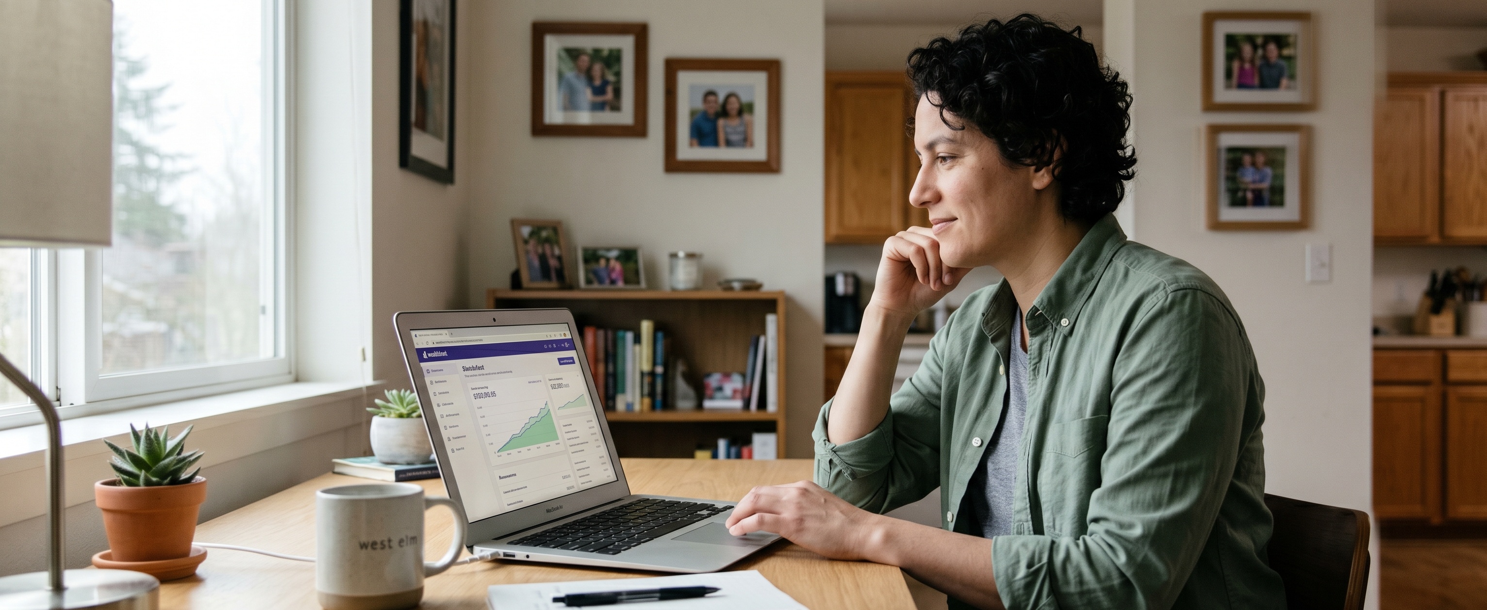 Woman reviewing her Wealthfront automated investment portfolio dashboard on a laptop at a home desk with a growth chart visible on screen