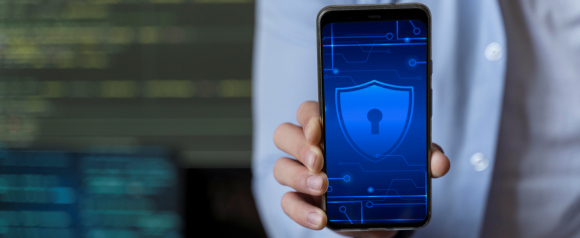 Person holding a smartphone displaying a glowing blue shield with a keyhole, symbolizing digital security and privacy. The image represents tools like CookieYes used in consent management platforms to protect user data and ensure compliance.