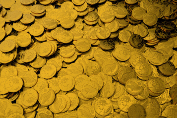 Gold coins neatly stacked and scattered on a reflective surface, symbolizing precious metal investments and retirement savings strategies such as a Gold IRA.