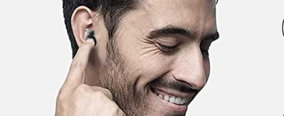 Smiling man inserting a Melosound in-ear hearing aid, with a close-up focus on the device and his expression of satisfaction. The image emphasizes ease of use and the compact, ergonomic design of the hearing aid.