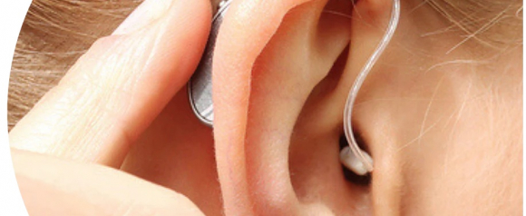 Close-up of a person’s ear with a behind-the-ear Soundwave hearing aid being adjusted by hand. The transparent tube curves into the ear canal, showing the discreet design and comfortable fit.