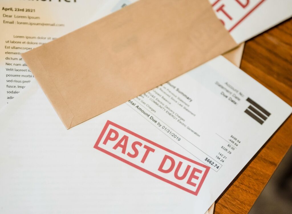 Stack of past due notices and bankruptcy papers illustrating the financial stress that leads people to ask are debt relief programs legit.