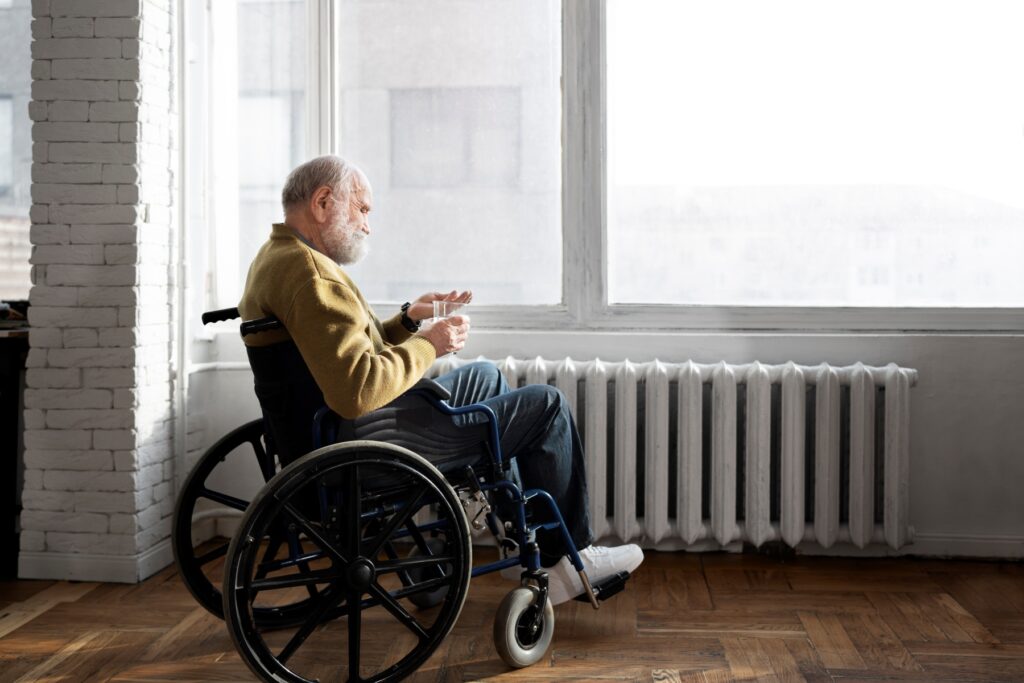 An elderly disabled adult in a wheelchair sitting by a window, representing individuals who may qualify for IRS tax forgiveness based on medical hardship.