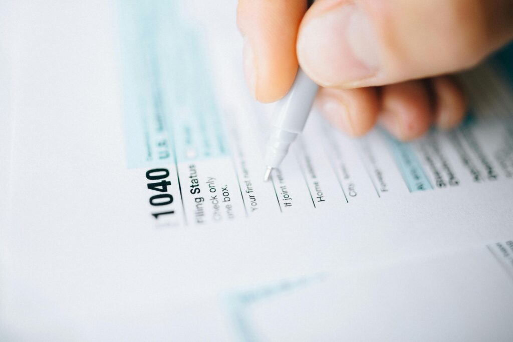 Close-up of a hand using a pen to fill out an IRS 1040 tax form, a necessary step before determining eligibility for Currently Not Collectible status.