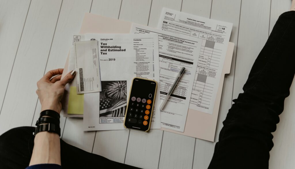 Person using a calculator over IRS Form 433-A (OIC) and tax documents, illustrating the financial analysis required for how to get an Offer in Compromise approved.
