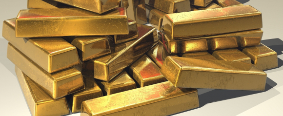 Pile of stacked gold bars with a slightly aged finish, arranged on a neutral surface with soft shadows. This image represents tangible asset security and aligns well with Noble Gold and Gold IRA investment topics.