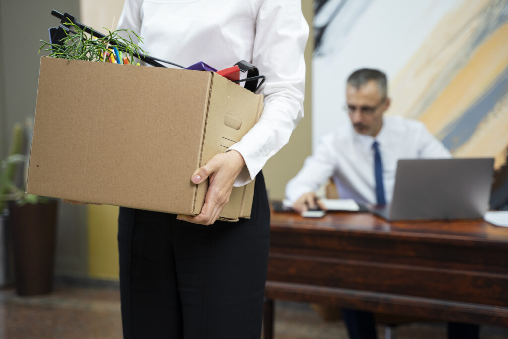 Side view of an employee carrying a box of personal belongings after a dismissal, illustrating a situation where consulting a wrongful termination lawyer may be necessary to review legal rights.