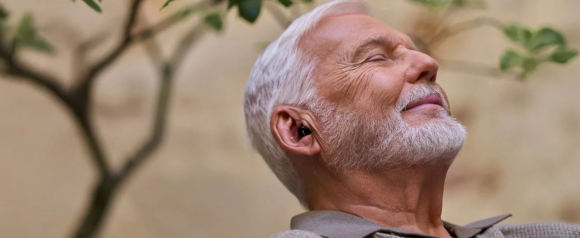 Senior man wearing Cearvol hearing aids outdoors with eyes closed, enjoying clear sound