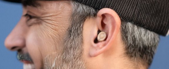 Close up side profile of a man wearing a discreet Oricle hearing aids device that fits snugly inside the ear canal. The image shows how Oricle hearing aids blend naturally with the ear for a low profile and comfortable everyday use.