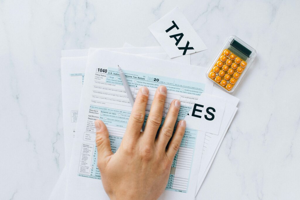 Hand using a calculator over IRS forms to estimate the total tax relief cost