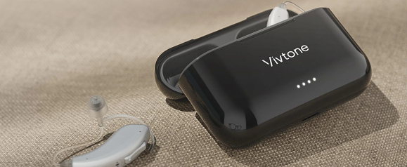 Black Vivtone hearing aids charging case with four LED indicator lights sits open on a beige fabric surface beside a slim gray hearing aid with a clear ear tube and soft silicone tip. The image highlights the compact Vivtone hearing aids design and portable charging case for convenient everyday use and easy storage.