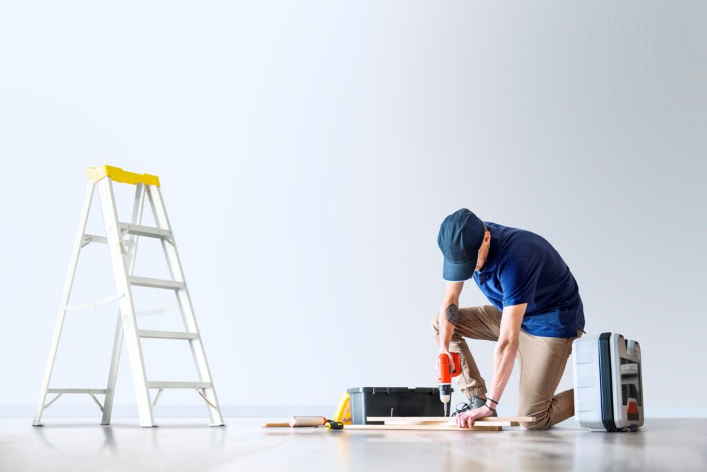 Contractor kneeling on floor using a power drill during a home improvement project