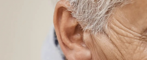 Close up of an older adult ear with a small discreet hearing aid fitted inside highlighting Nebroo hearing aids designed for subtle and comfortable daily use.