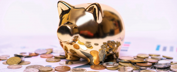 Gold piggy bank surrounded by scattered coins on financial papers. Symbol of saving and managing money with personal loans from Citibank.