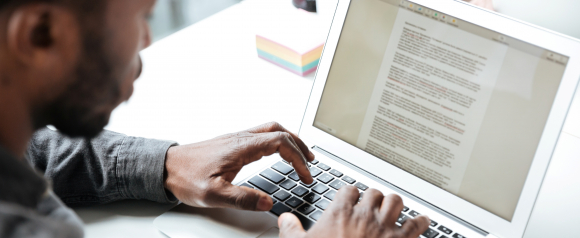 Man reviewing and signing documents on a laptop using a remote online notary platform like BlueNotary