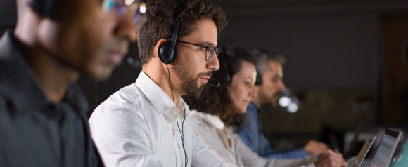 Customer support team wearing headsets works on laptops in a call center environment, illustrating how RingCentral business phone systems powered by VoIP help teams manage customer communication and incoming calls efficiently.