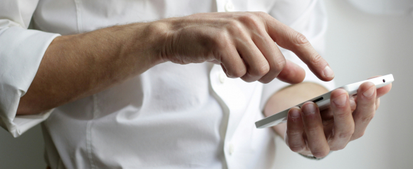 Person using a smartphone and tapping the screen to manage a call or message, representing how Zoom Phone business phone systems powered by VoIP enable mobile communication and remote work.