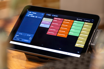 Toast POS touchscreen terminal on a restaurant counter displaying a color-coded menu ordering screen
