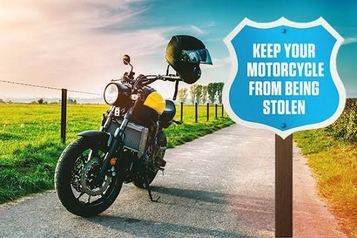 Motorcycle with a helmet parked on a country road beside a blue shield sign reading keep your motorcycle from being stolen