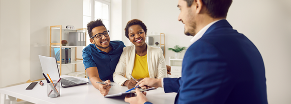 Smiling couple meeting with a mortgage loan officer to sign paperwork at a desk