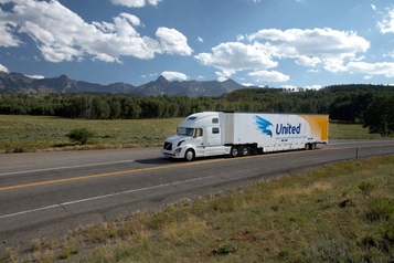  A white United Van Lines tractor-trailer with the blue eagle logo driving on a mountain highway