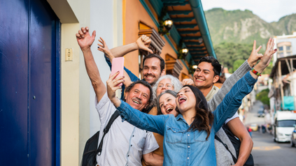 Cheerful multigenerational family taking a group selfie on a colorful street while traveling.