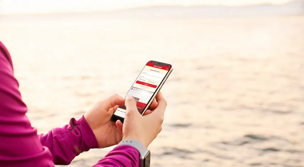 Person logging into the Wells Fargo mobile banking app on a smartphone outdoors near the water.